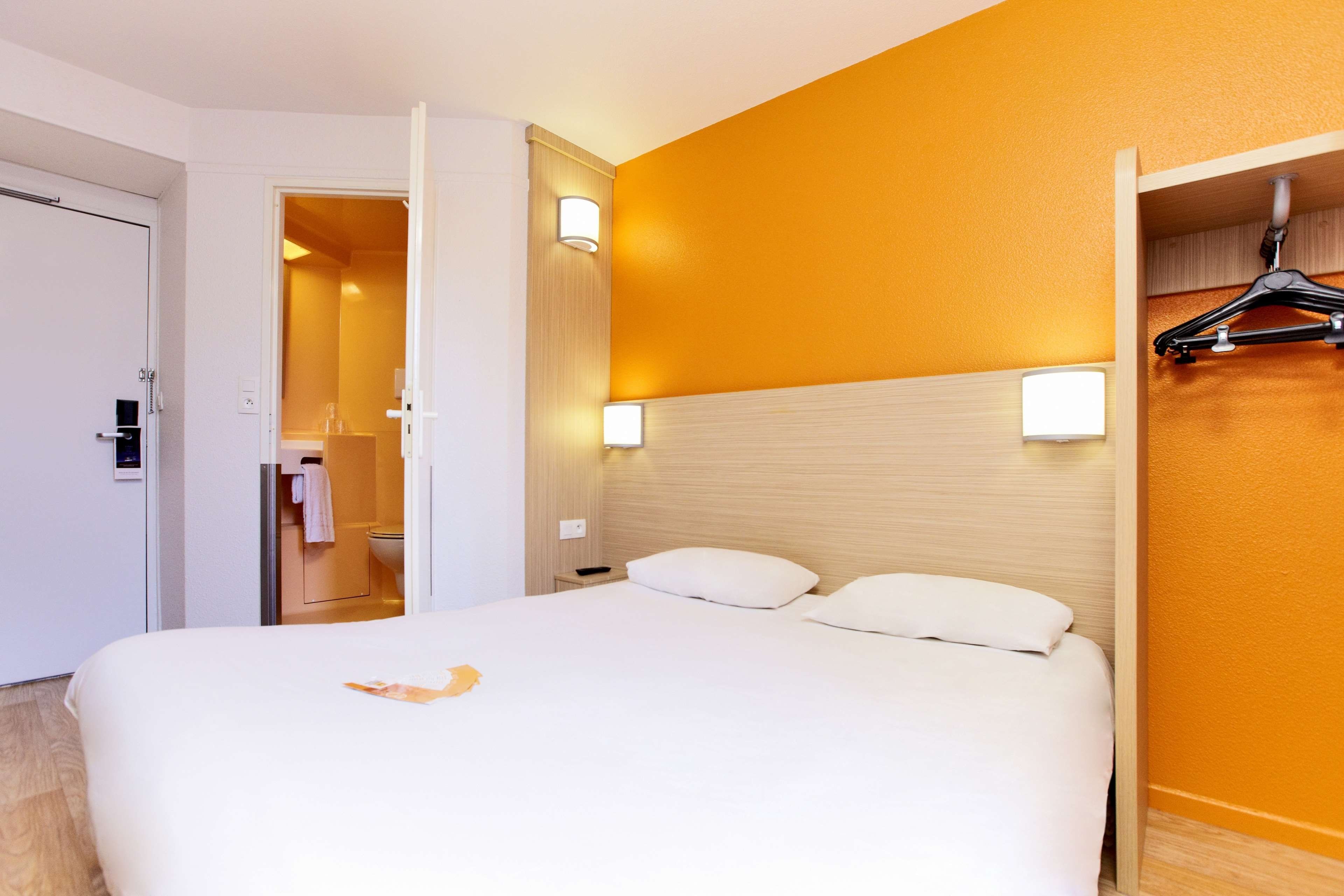 Una habitación de hotel con cama, baño y armario.