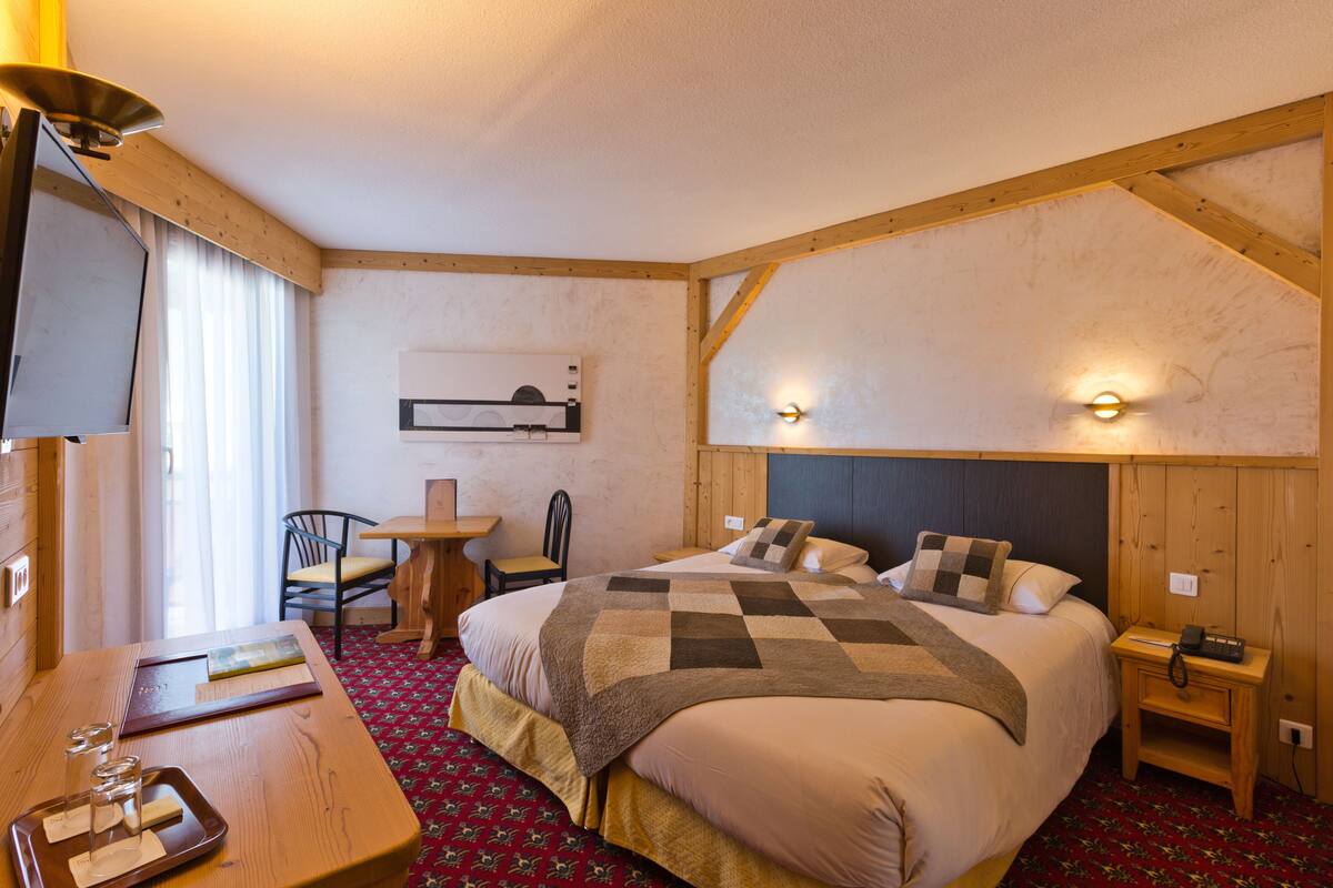Habitación de hotel con una cama grande, un escritorio con silla, un televisor y una mesita con bandeja.