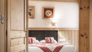 Ein Schlafzimmer mit Holzbalkendecke, einem Bett mit roter Bettwäsche, einem Kopfteil und einer Wandleuchte.