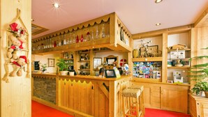 Eine Bar mit Holztresen, bequemen Sitzhocker, roten Teppich und Holzregalen mit diversen Gegenständen.