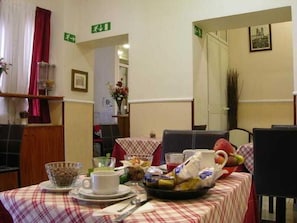 Un comedor con una mesa dispuesta para el desayuno, que incluye un tazón, una taza y una cesta de fruta.