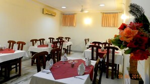 Un comedor con varias mesas, sillas y una planta decorativa.