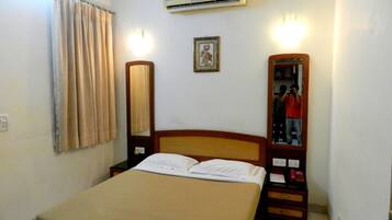 Una habitación de hotel con una cama, una mesita de noche, un espejo, aire acondicionado y un cuadro en la pared.