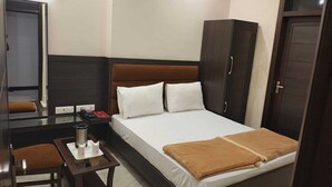 Habitación de hotel con cama, escritorio, silla, armario y espejo.