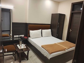 A hotel room with a bed, a desk, a chair, a wardrobe, and a mirror.