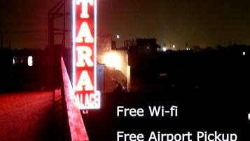 A neon sign for a hotel named "HOTEL TARA" in Central Delhi, with amenities including free Wi-Fi, airport pickup, and breakfast.
