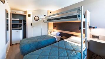 Ein kleines Zimmer mit Etagenbett, Schreibtisch, Mikrowelle und Kühlschrank.
