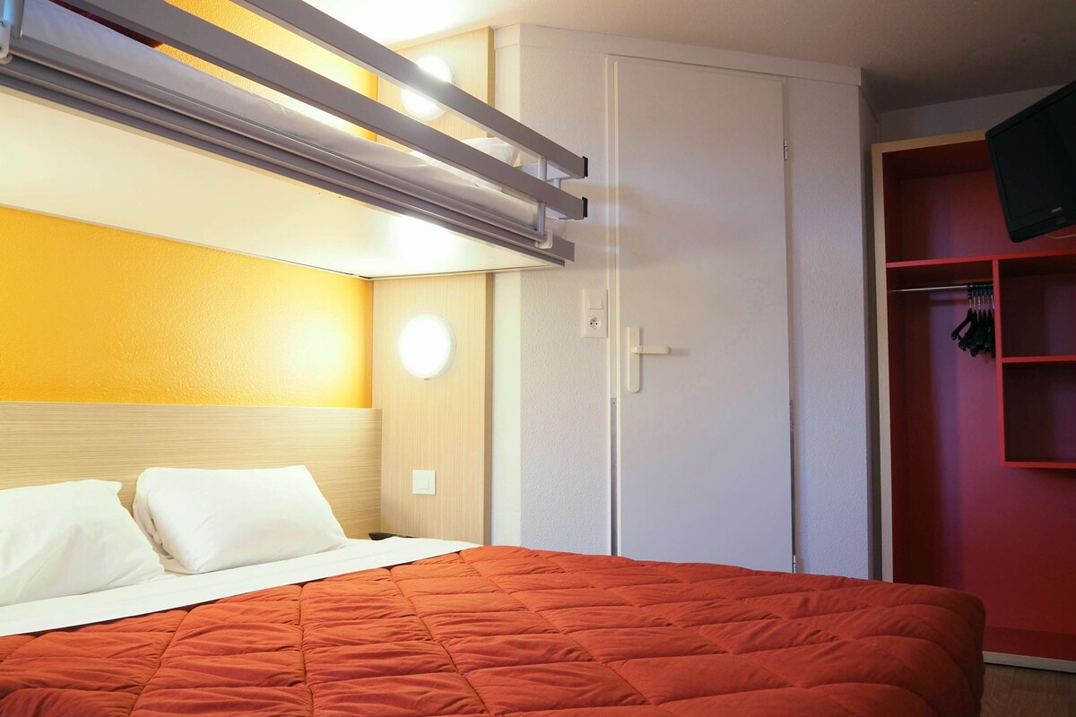 Una habitación de hotel con una cama, un armario y una pared roja.