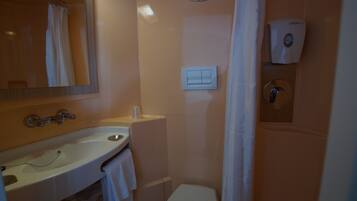 A bathroom with a sink, mirror, toilet, and a hand dryer.