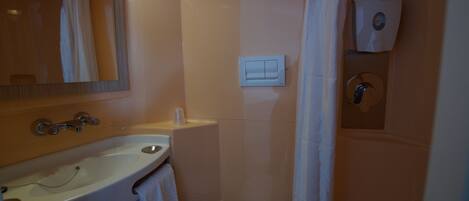 Un baño con lavamanos, espejo, inodoro y secamanos.