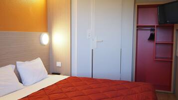 Une chambre d’hôtel avec un lit, une armoire et un téléviseur.