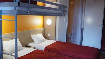 A bunk bed with a red quilt, a bedside table, and a wall-mounted light.