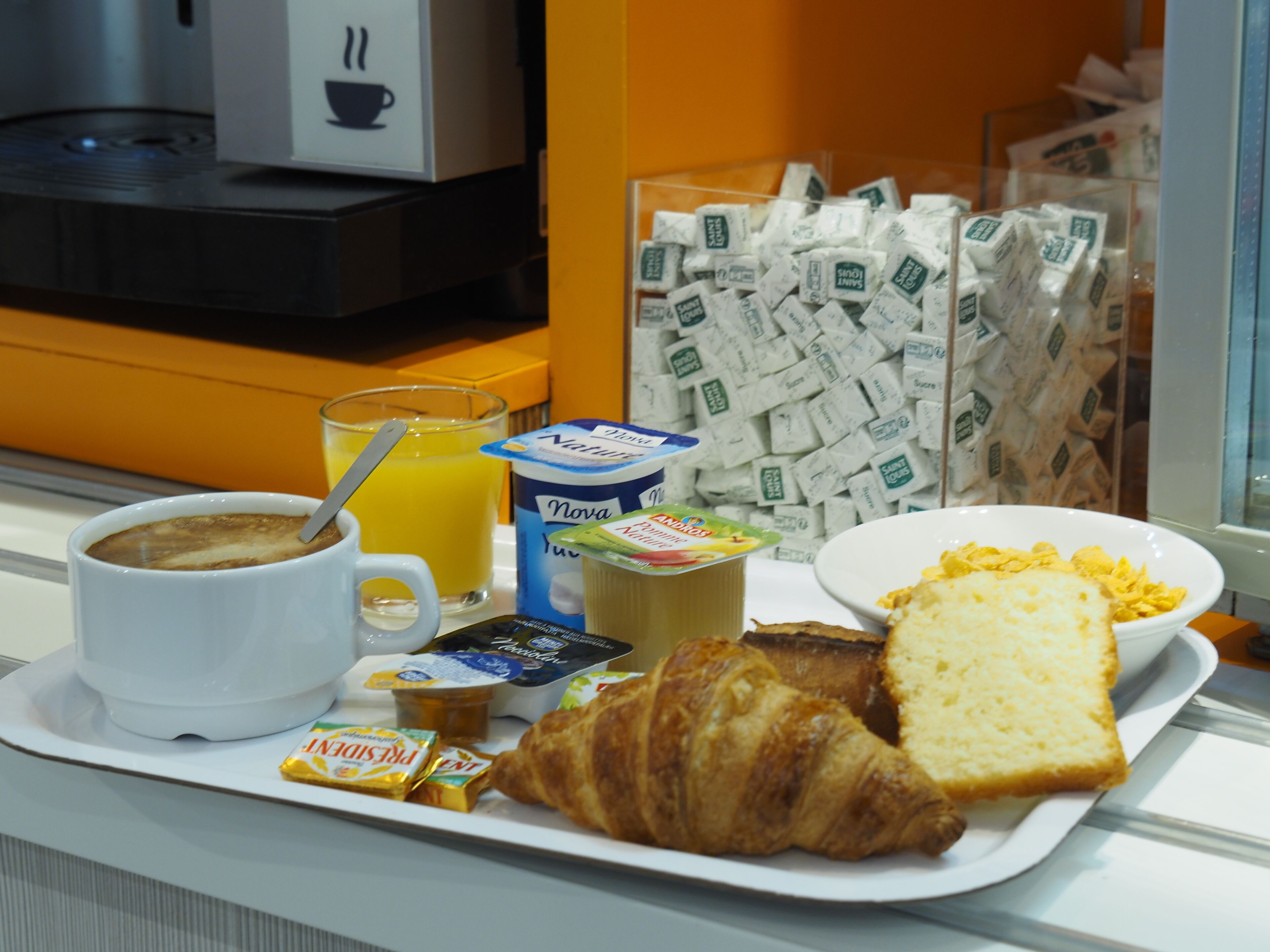 Een ontbijfwagen met koffie, sinaasappelsap, yoghurt, croissant en brood.