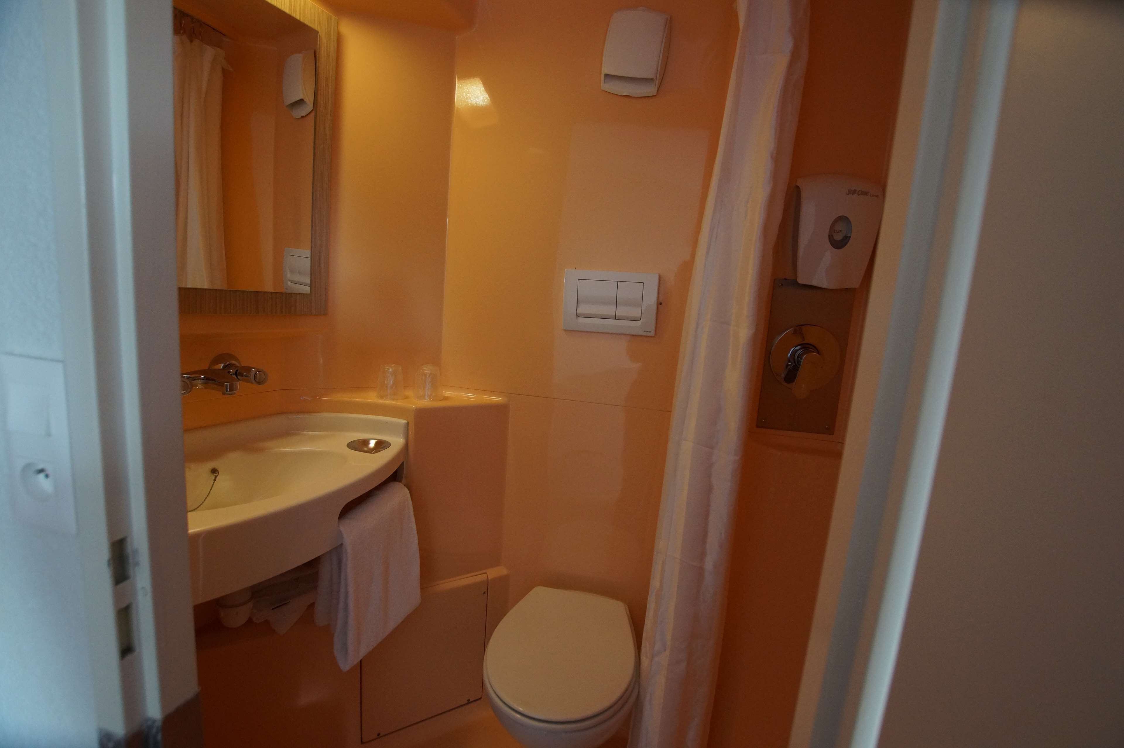 Baño pequeño con lavamanos, espejo, inodoro y cortina de ducha.
