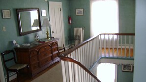 A staircase with a wooden handrail and white balusters, leading to a lower level. - Four Creeks Bed & Breakfast (Girard)