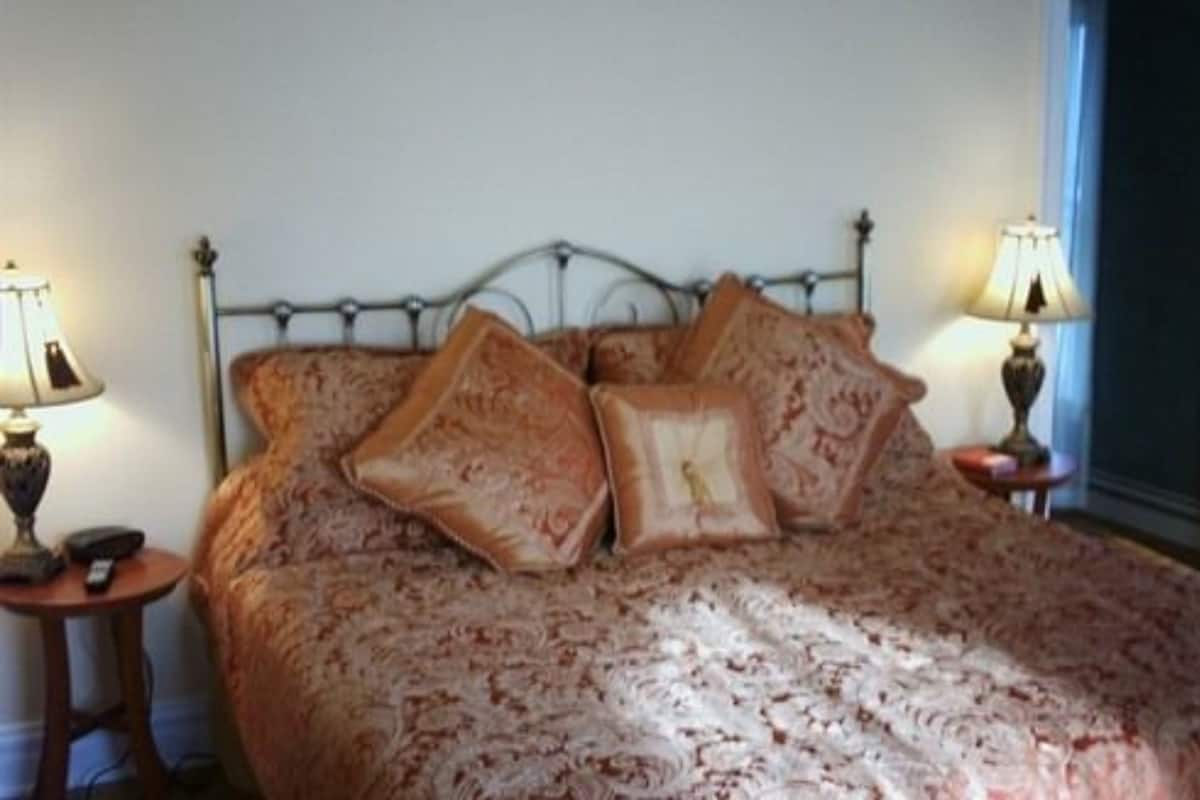 A bed with a patterned bedspread, two bedside tables with lamps, and a metal headboard.