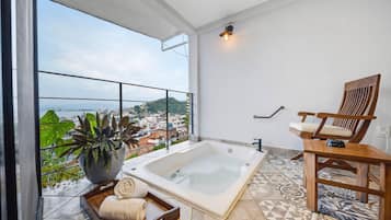 Ein modernes Badezimmer mit einer großen Badewanne, einem Holzstuhl und einem Topf mit Pflanze.