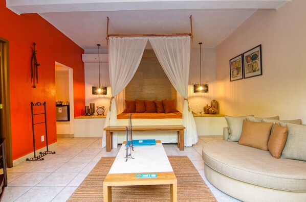 Un dormitorio con cama, mesita de noche y sofá.