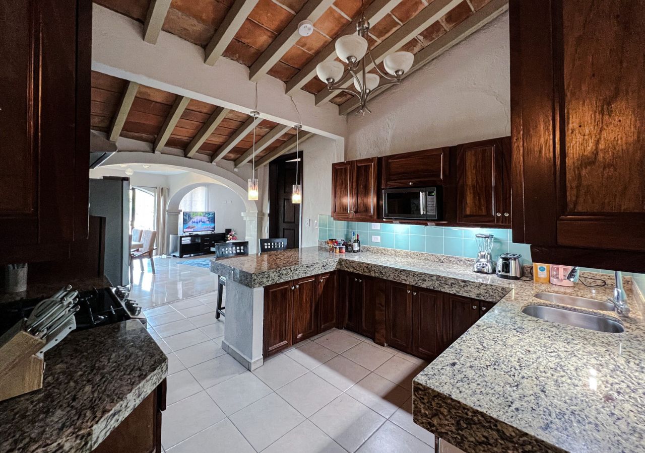 A spacious kitchen with granite countertops, wooden cabinets, and a central island.