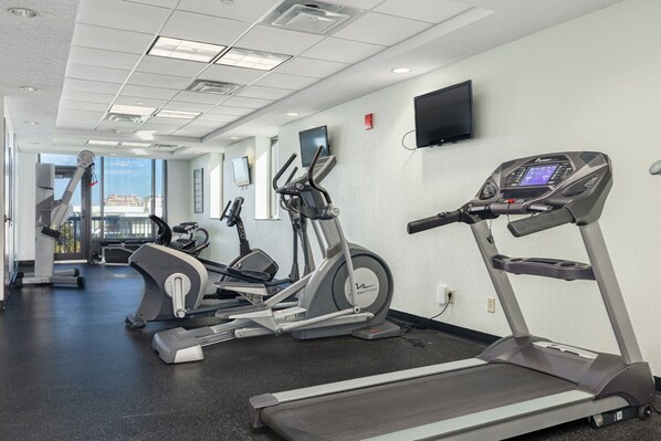 Un gimnasio con cintas de correr, elípticas y una bicicleta estática.