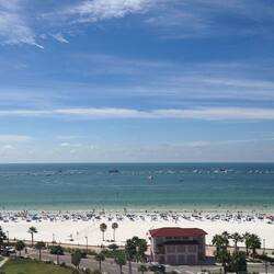 Enjoy beach activities like boating and lounging on the sandy beach, surrounded by palm trees and a pier.