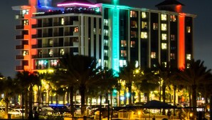 A multi-story hotel with balconies, illuminated by colorful lights.