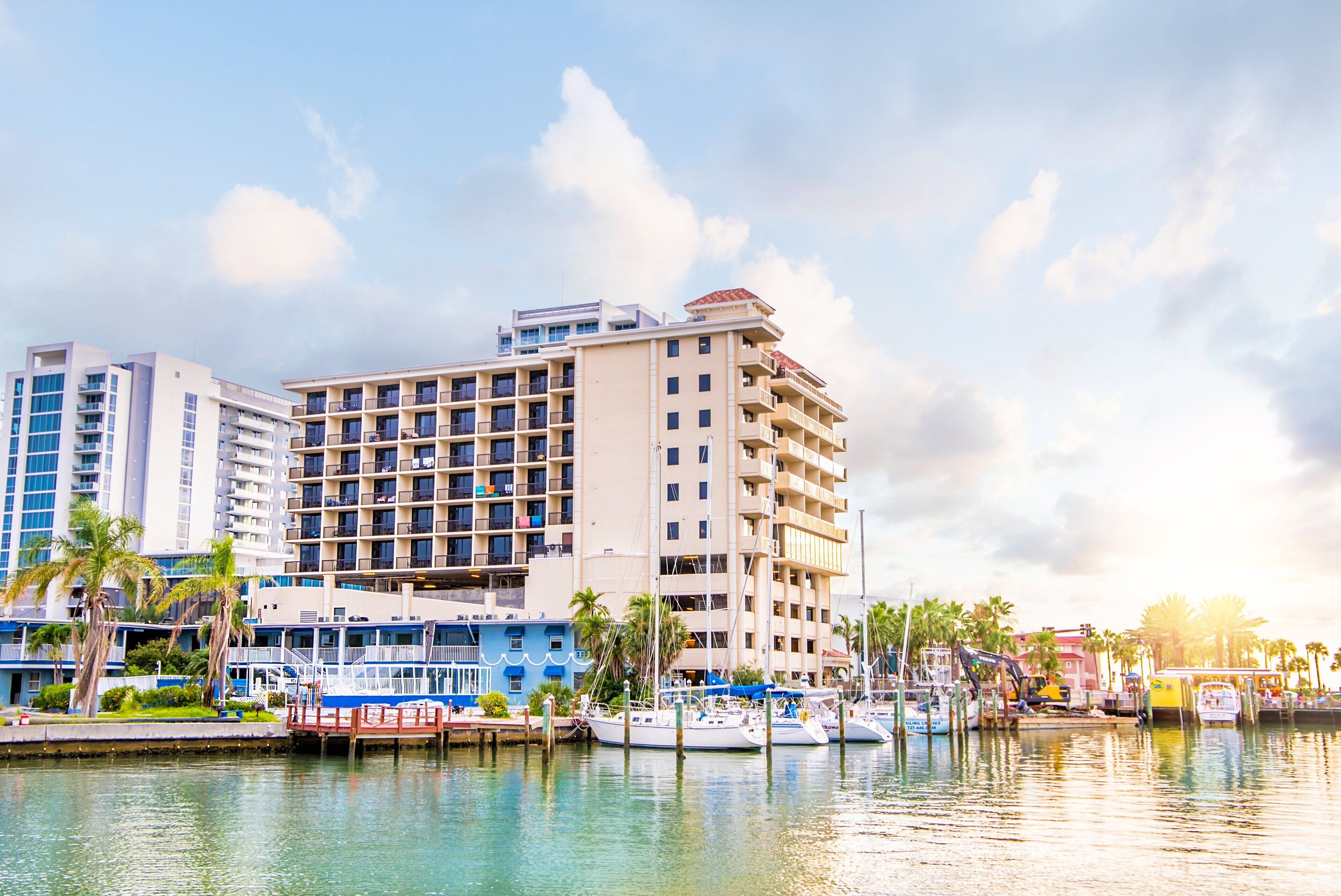 A waterfront hotel with multiple balconies, a marina with boats, and palm trees.