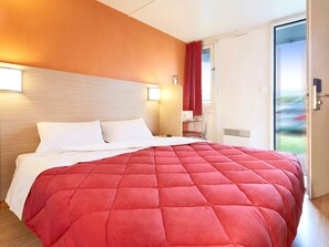 A hotel room with a large bed, a wooden headboard, a red curtain, and a view of the outdoors. - Premiere Classe Saint Quentin (Saint-Quentin)