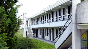 A building with a covered walkway and picnic tables. - Premiere Classe Saint Quentin (Saint-Quentin)
