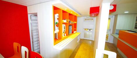 Un pasillo bien iluminado con paredes naranja y blanco, suelo de madera y un mostrador con varios artículos.