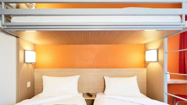 A bunk bed room with two beds, each with a red quilted bedspread, and a wooden headboard. - Premiere Classe Saint Quentin (Saint-Quentin)