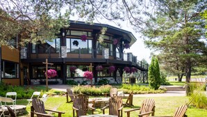A lodge with a stone fire pit, wooden Adirondack chairs, and hanging flower baskets.