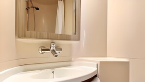 Une salle de bain moderne avec un lavabo blanc, un robinet chromé et un miroir au-dessus.