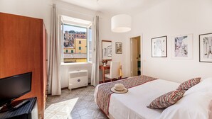 A hotel room with a bed, a desk, a chair, a television, and a window with a view of buildings. - Hotel Rio Sul Mare (Rio)