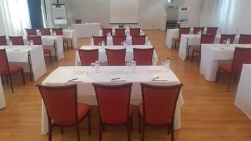 A conference room with multiple tables and chairs, white tablecloths, and water bottles.