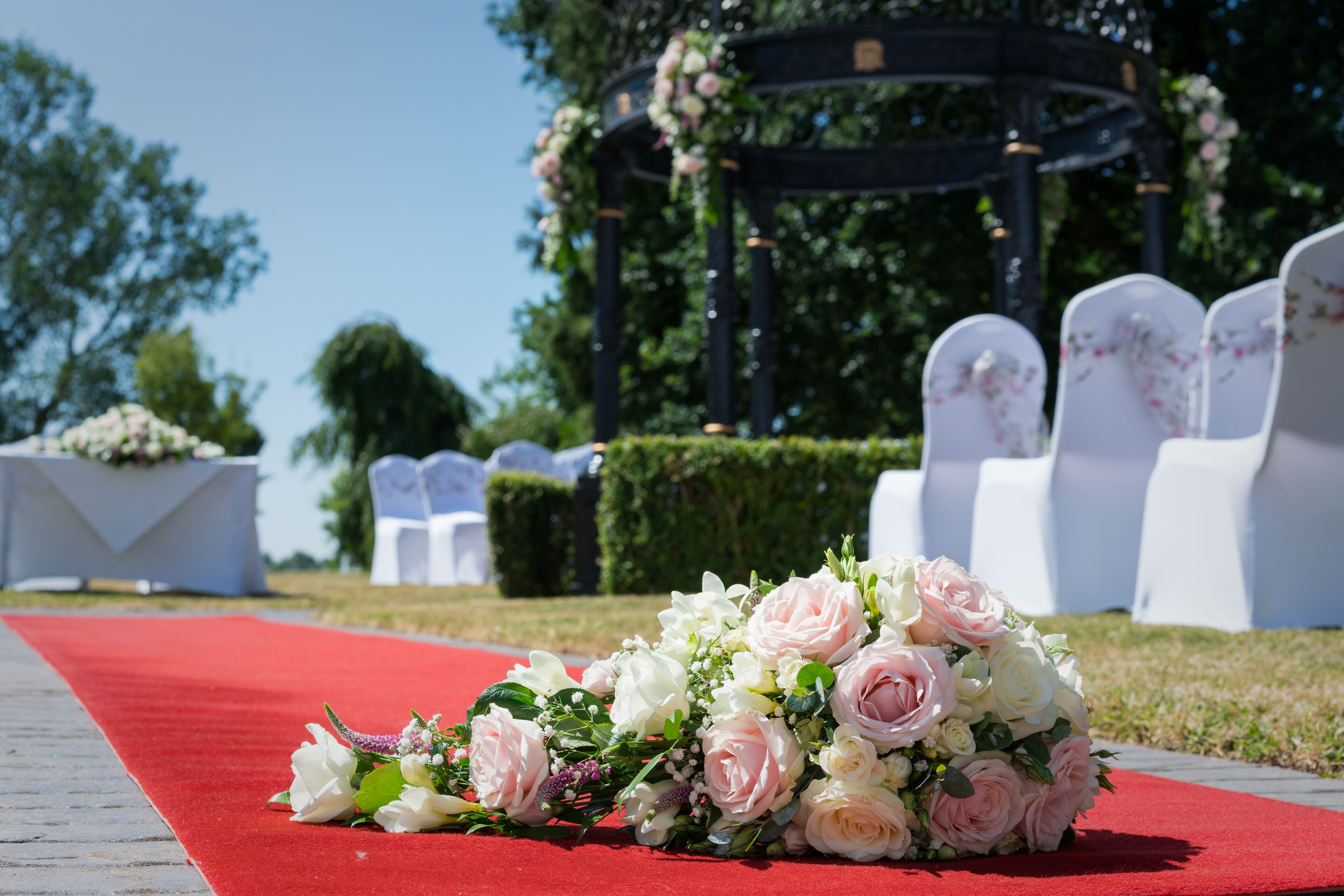 A red carpet leading to a gazebo with white chairs and floral decorations.
