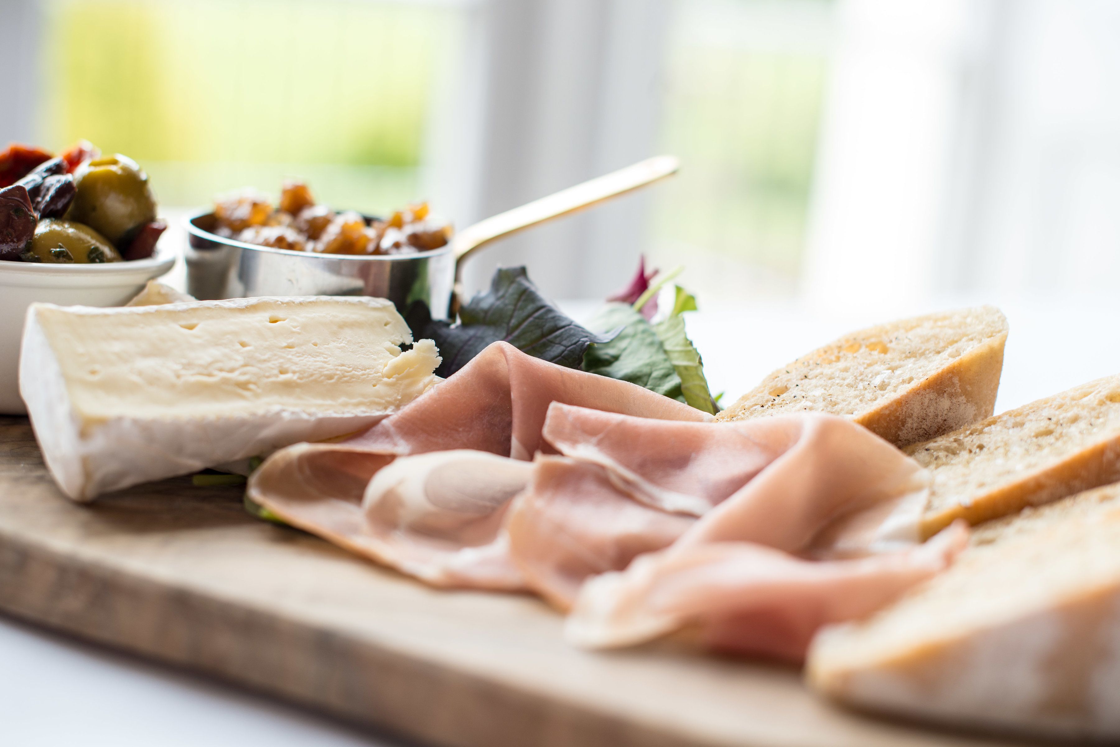 Une sélection de fromages, de charcuteries et de pains présentés sur une planche en bois.