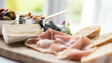 A variety of cheeses, meats, and bread on a wooden board.