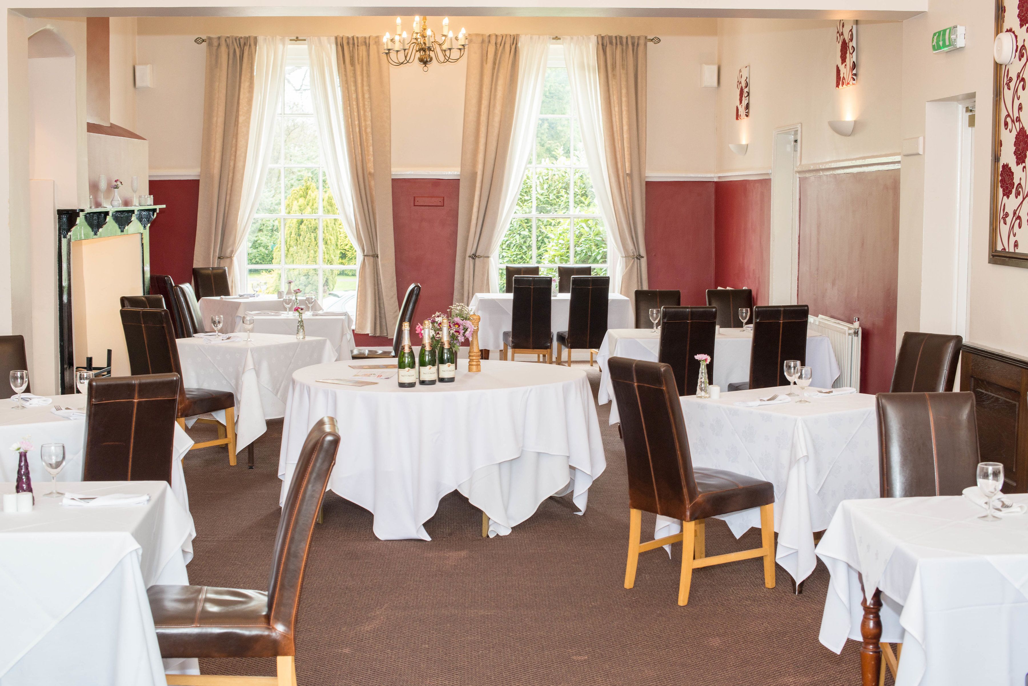 A dining area with round tables, chairs, and a chandelier.