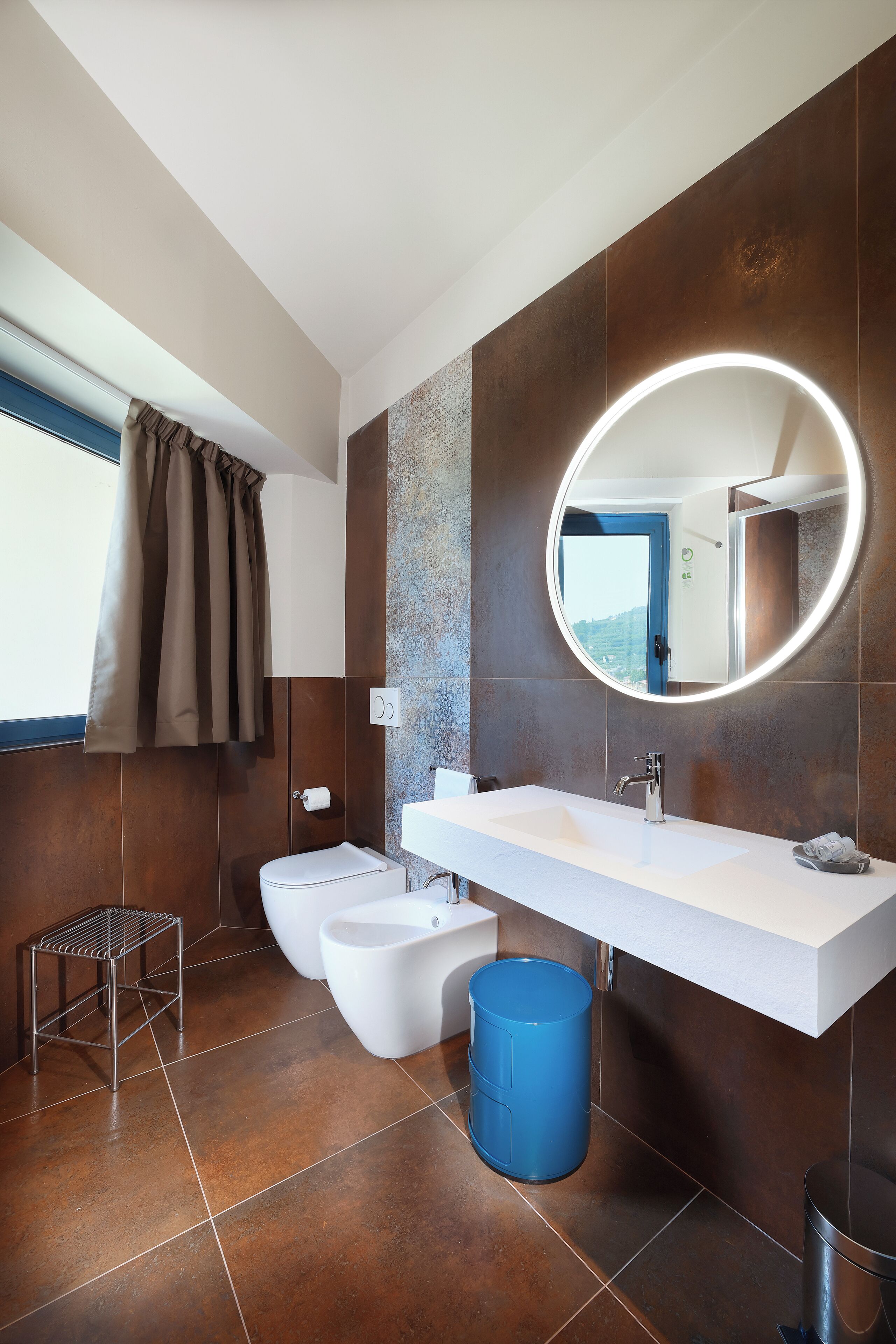 A modern bathroom with a large mirror, two sinks, and a toilet.