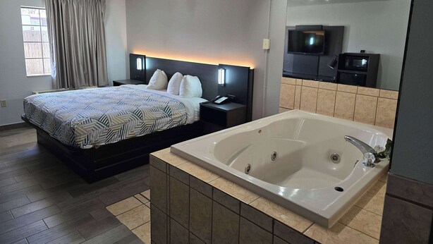 A modern hotel room with a large bed, a separate bathroom with a bathtub, a flat-screen TV, and a microwave. - Motel 6 Oklahoma City, OK - Frontier City (Oklahoma City)