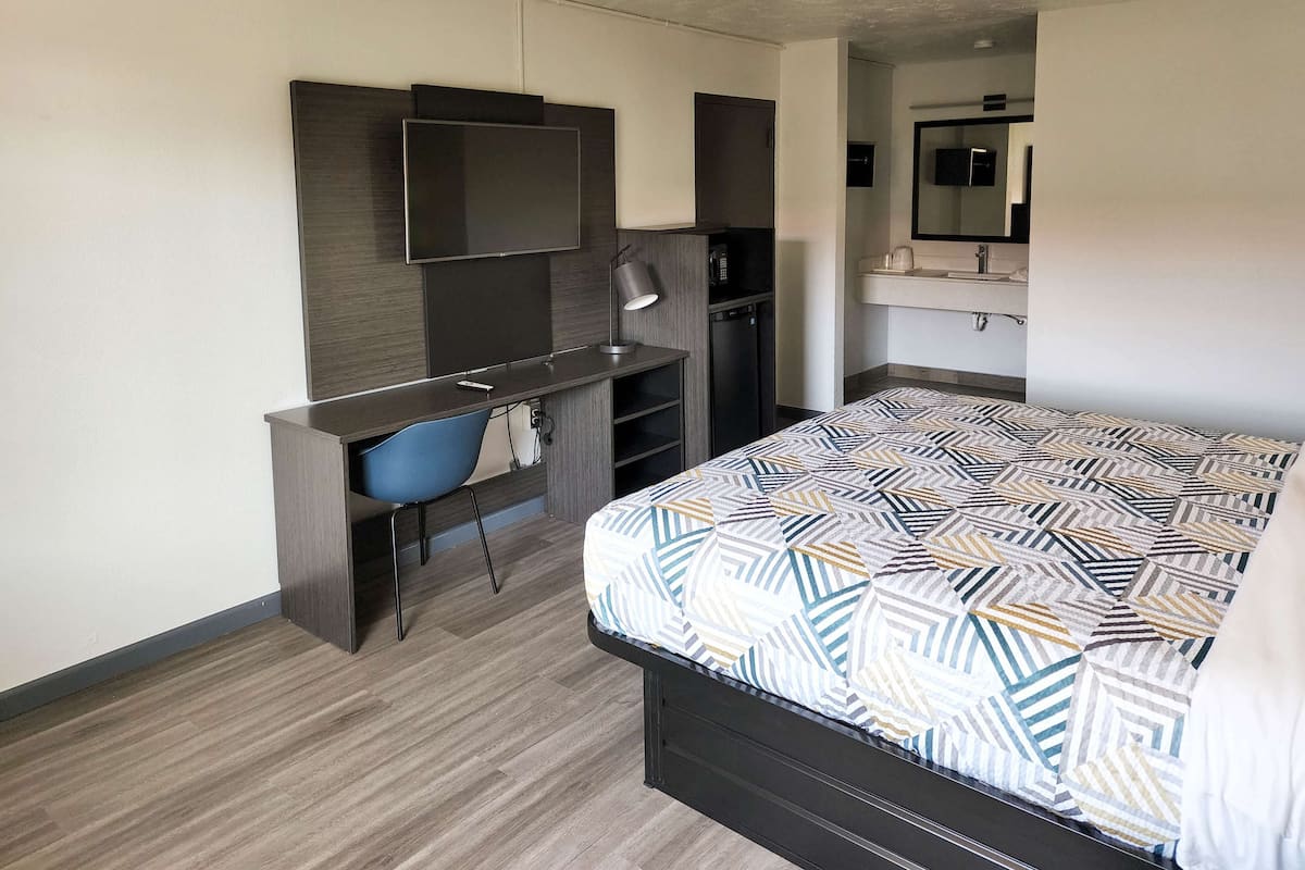 Une chambre à coucher comprenant un lit, un bureau, une chaise, un téléviseur et une armoire.