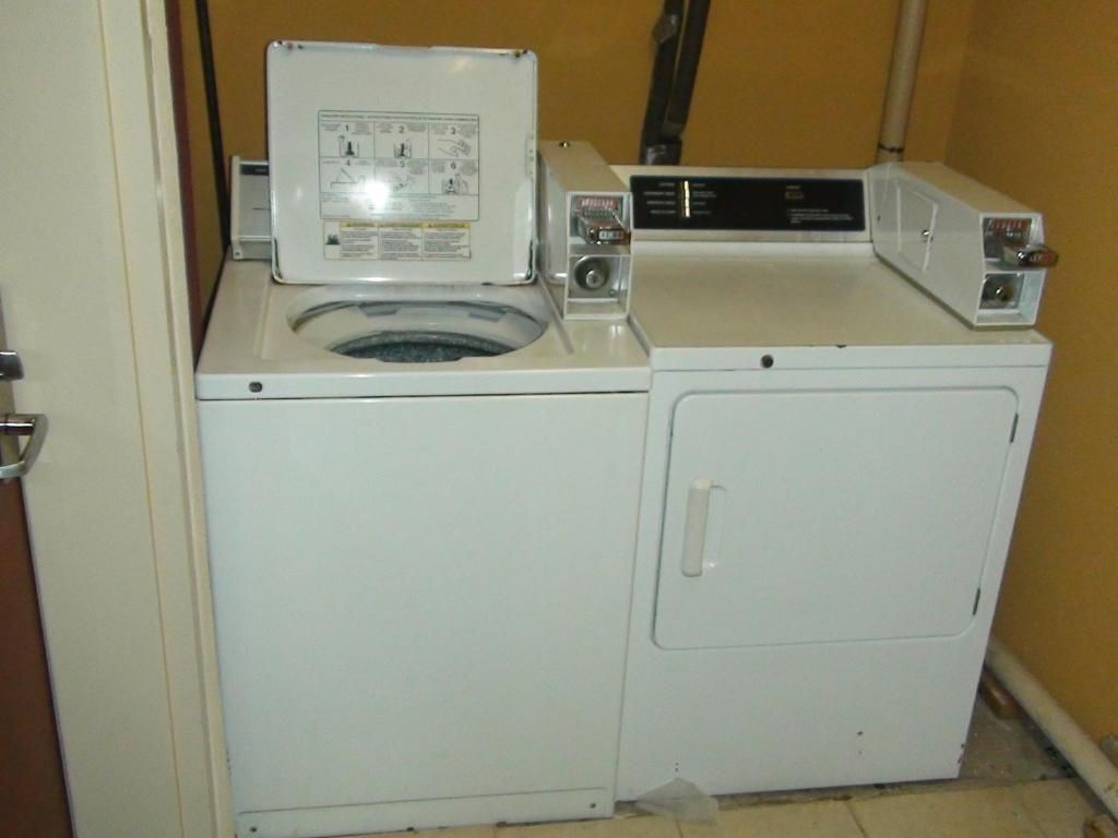 A compact laundry area with a washing machine and dryer, a door, and a wall-mounted electrical outlet.