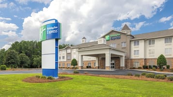 Un hotel Holiday Inn Express con un letrero grande, una entrada cubierta y un estacionamiento.