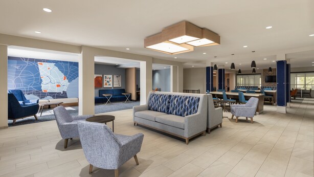 A spacious lobby with seating areas, a map on the wall, and a modern ceiling design. - Holiday Inn Express Savannah Airport by IHG (Savannah)