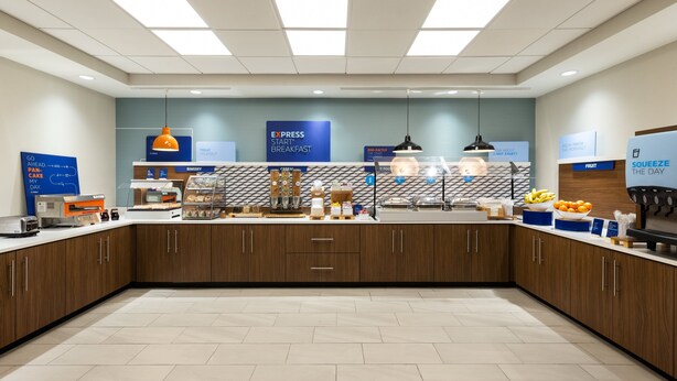 A modern breakfast area with a counter, kitchen appliances, and a sign for 'EXPRESS START' breakfast. - Holiday Inn Express Savannah Airport by IHG (Savannah)