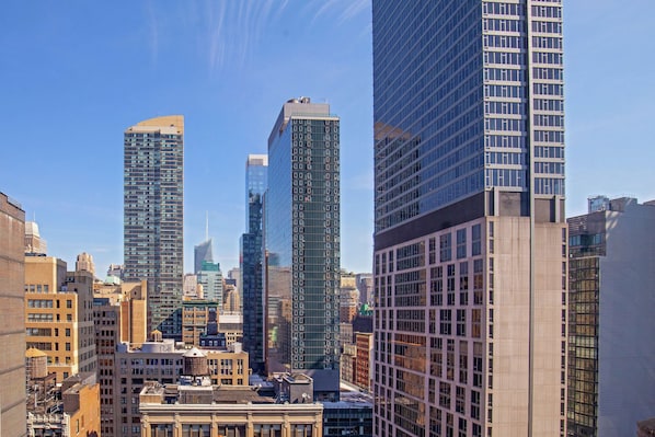 A cityscape with modern high-rise buildings, including a prominent glass skyscraper and a historic building with a classic facade.