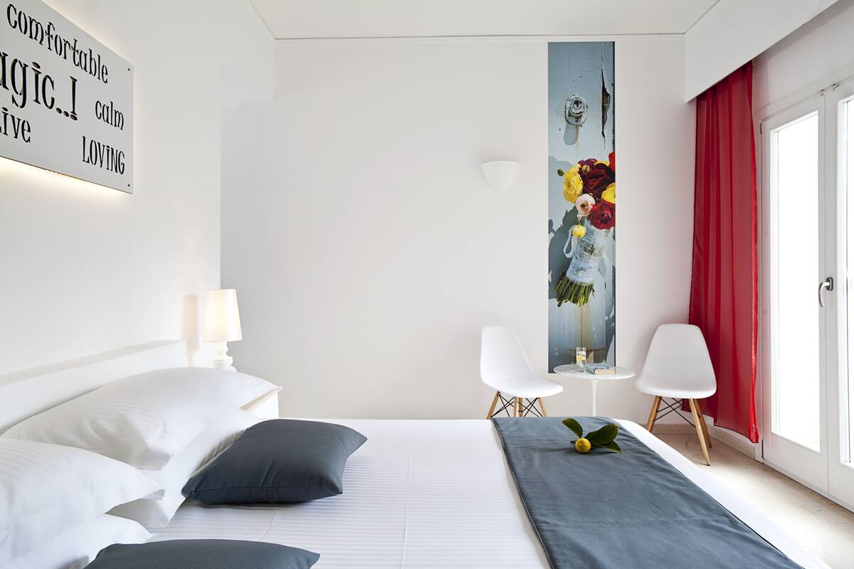 Une chambre d’hôtel moderne avec un lit soigneusement fait, un tableau accroché au mur et un rideau rouge.