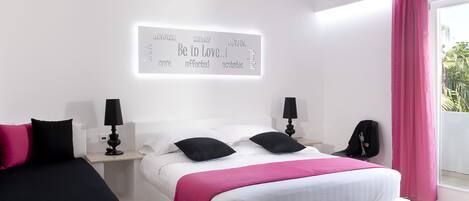 Un dormitorio moderno con cama, mesitas de noche, una lámpara de pared y un ventanal con cortinas.