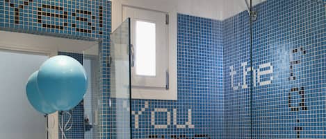 A bathroom with a sink, mirror, and shower area.